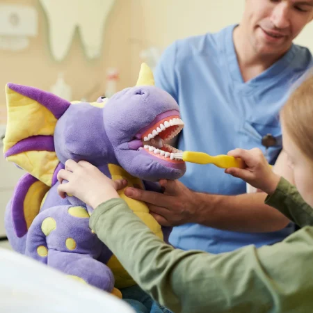 girl-brushing-plush-dinosaur-s-teeth-at-dentist-vi-2026-03-25-05-22-48-utc